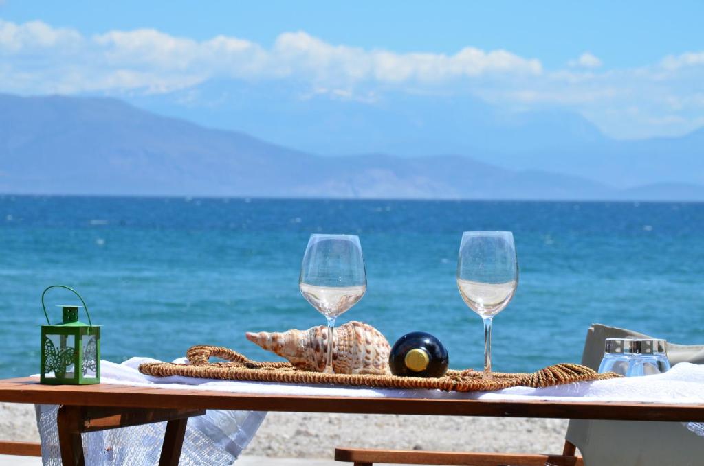 a table with two wine glasses on the beach at Maison de la mer in Témeni