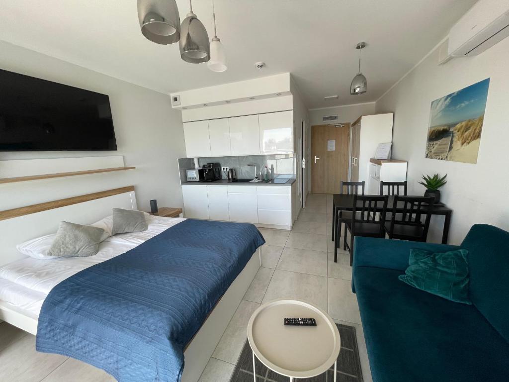 sypialnia z łóżkiem i kanapą oraz kuchnia w obiekcie Kasprowicza 20 Luxury Apartments - Free Pool, Saunas, Salzgrotte, Jacuzzi, Gym, Children's Playroom, Fitness w Kołobrzegu