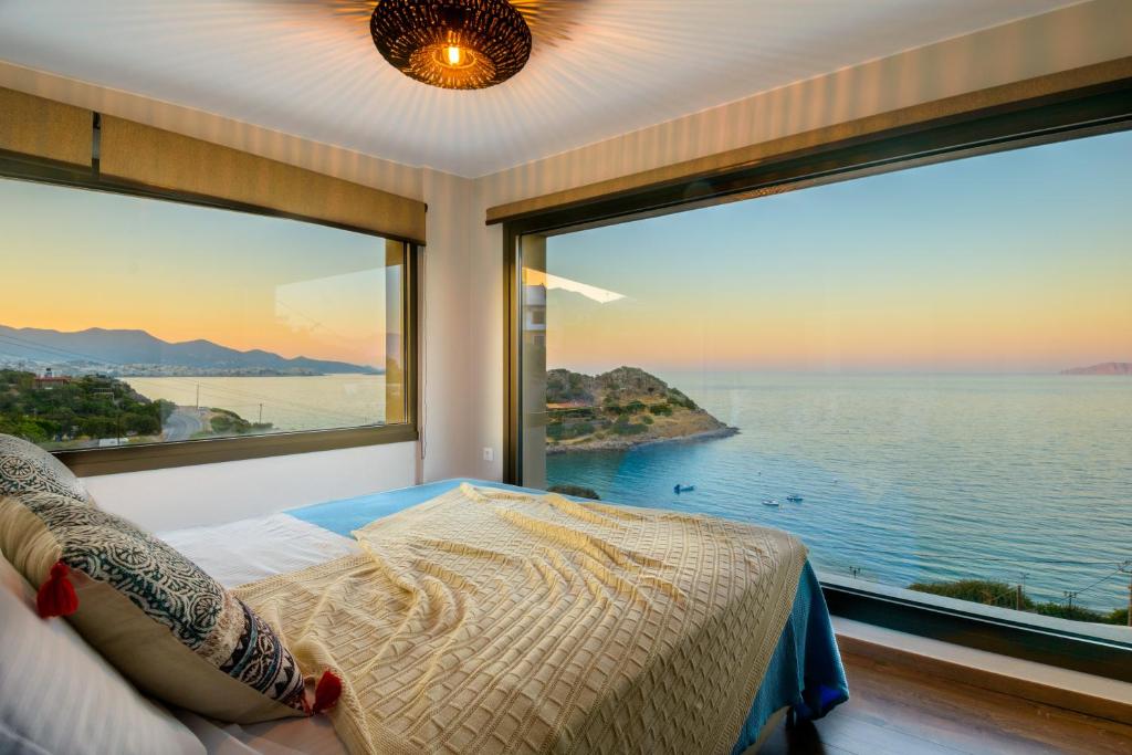 a bedroom with a large window overlooking the water at Beachfront Villa Phi φ in Agios Nikolaos