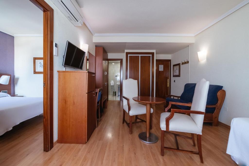 アルメリアにあるTorreluz Apartamentosのベッド、テーブル、椅子が備わるホテルルームです。