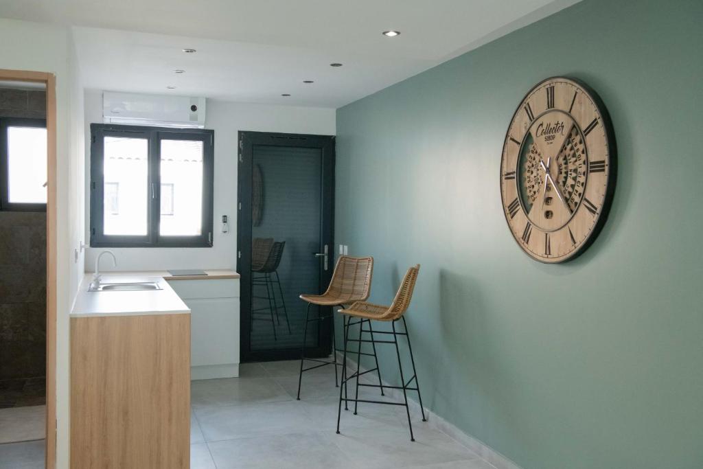 a kitchen with a clock on a wall with stools at Studio meublé avec terrasse in Port-de-Bouc
