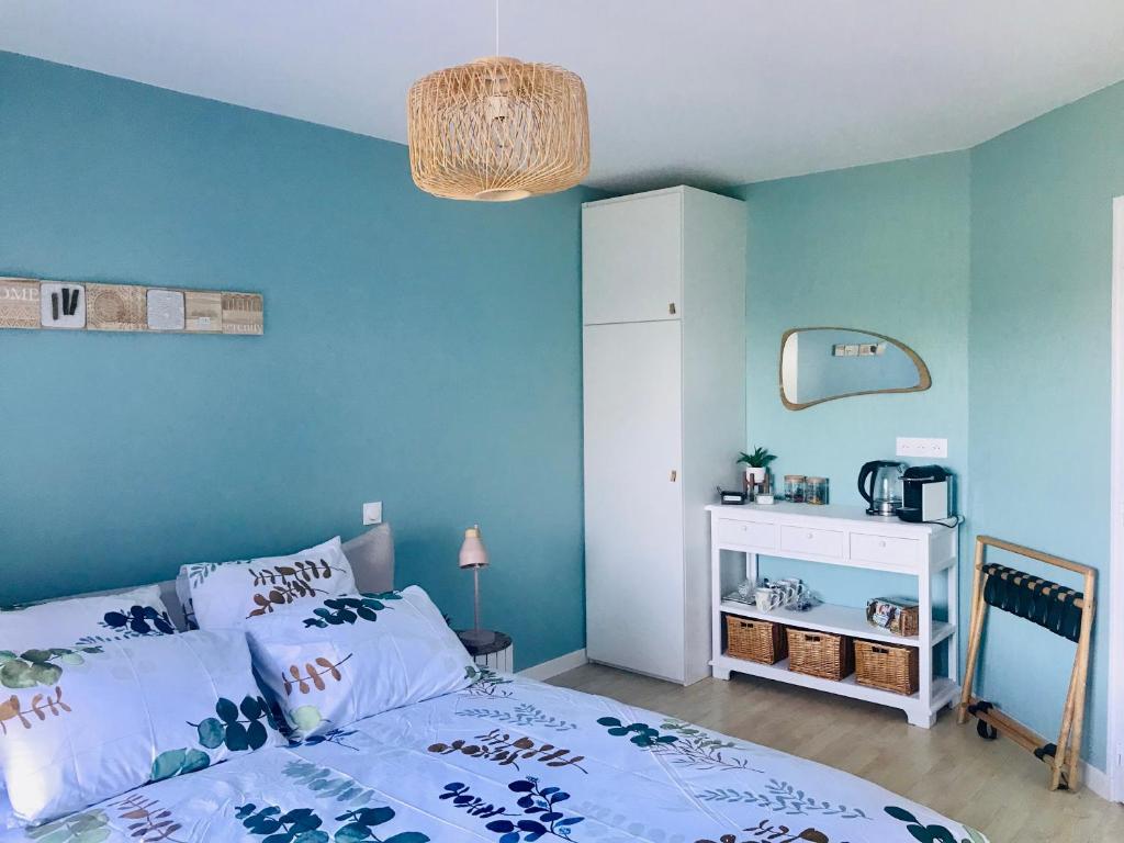 1 dormitorio con cama y pared azul en Au petit bonheur de Claire et Jo, en La Chapelle-Caro