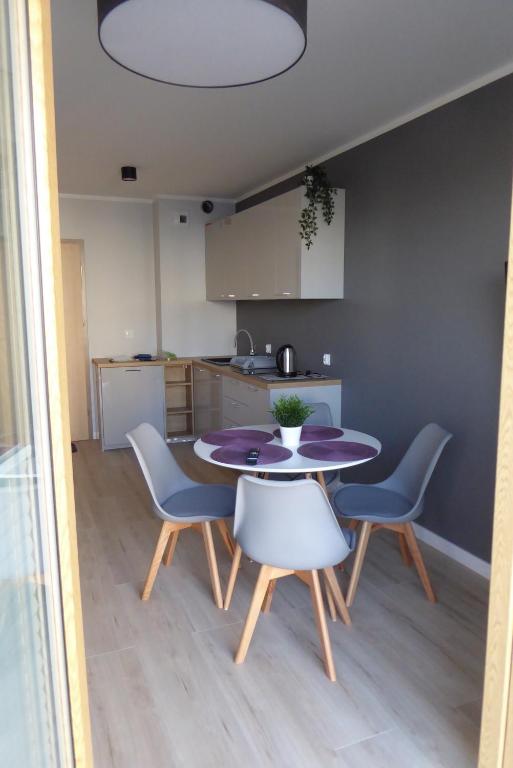 a kitchen and a table and chairs in a room at Dziwnówek Słoneczne Tarasy Gray in Dziwnówek