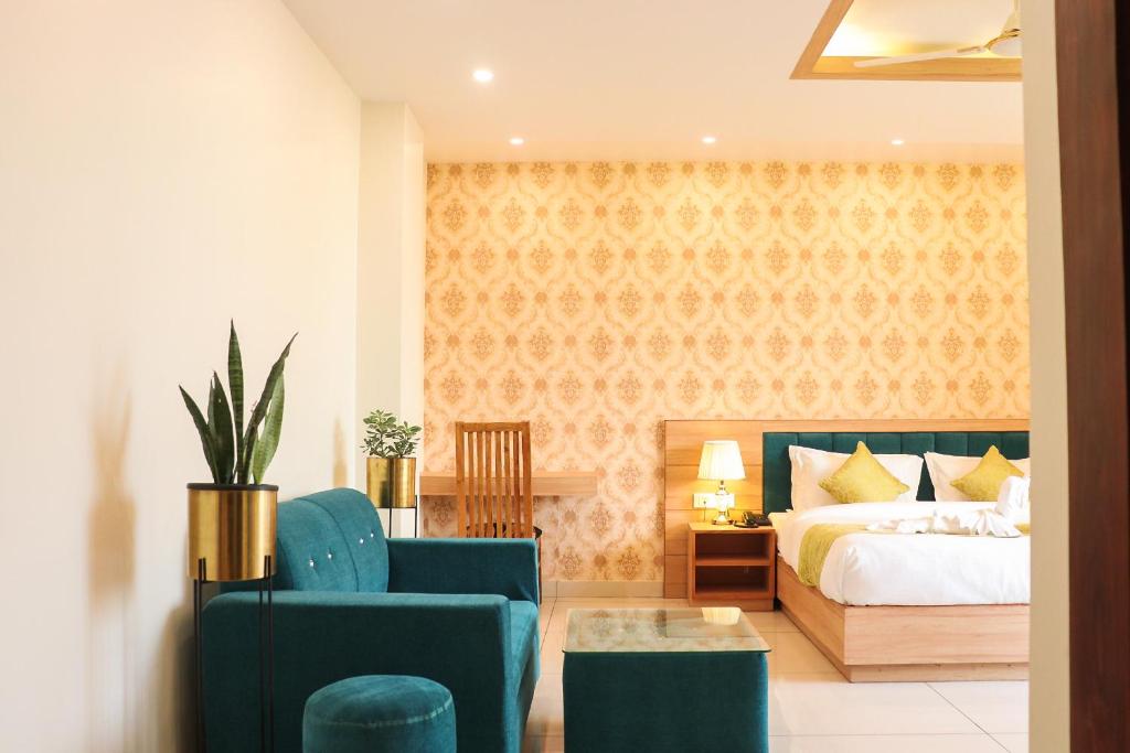 um quarto com uma cama e duas cadeiras azuis em Hotel Royal Palm Dehradun em Dehradun