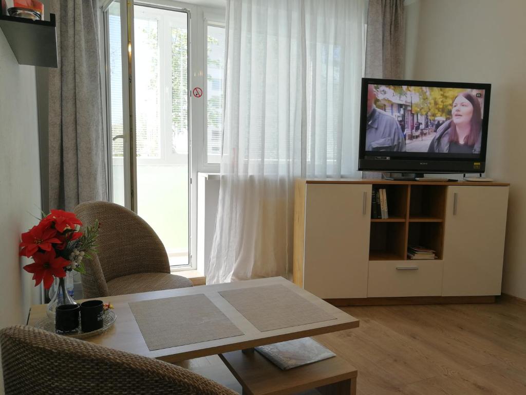 una sala de estar con un televisor y una mesa en Šiauliai City Apartment, en Šiauliai