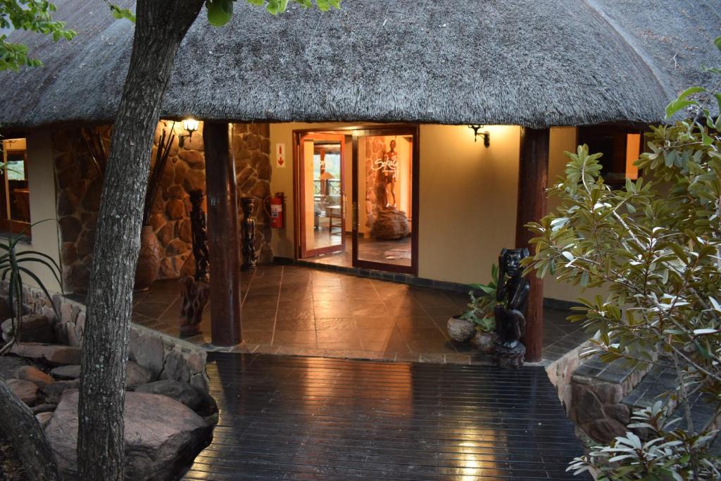 een toegang tot een huis met een rieten dak bij Sekala Private Game Lodge in Welgevonden Wildreservaat