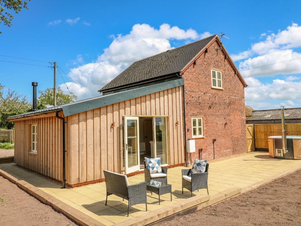 a small brick house with chairs on a patio at Acorn Lodge in Stafford