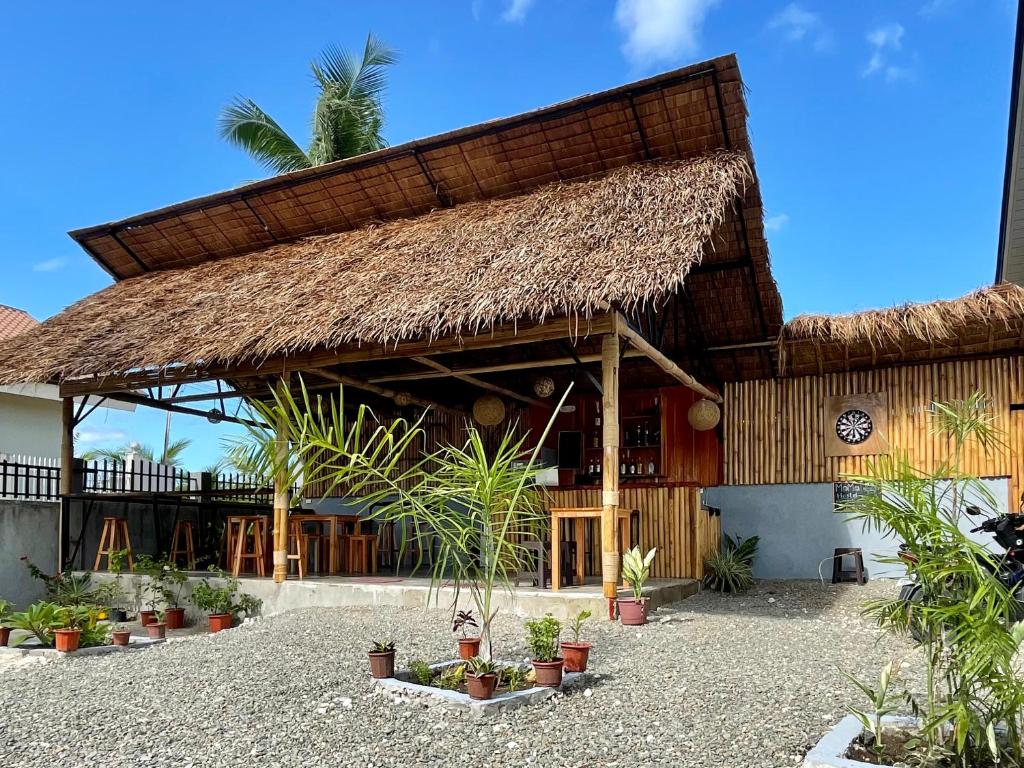 a resort with a thatched roof and potted plants at MOMO Hostel in Moalboal