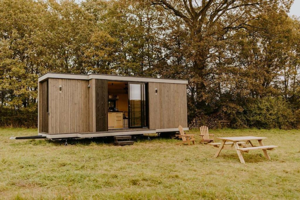 eine kleine Hütte auf einem Feld mit einem Picknicktisch in der Unterkunft Parcel Tiny House I Le P'tit Clos Normand 