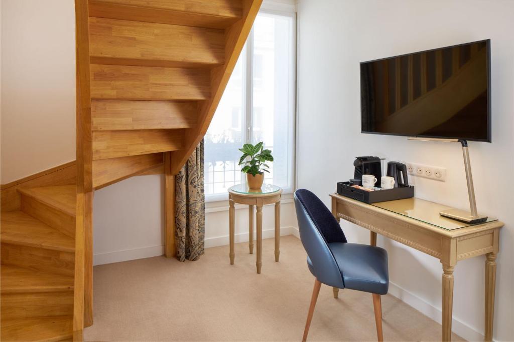 a room with a desk and a tv on a wall at Hotel Villa Romantic &amp; Spa in Paris