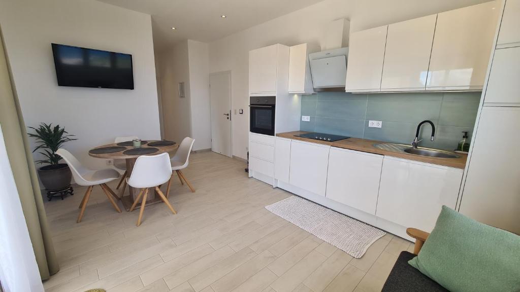 a kitchen with white cabinets and a table and chairs at Apartments Tanja in Zavalatica