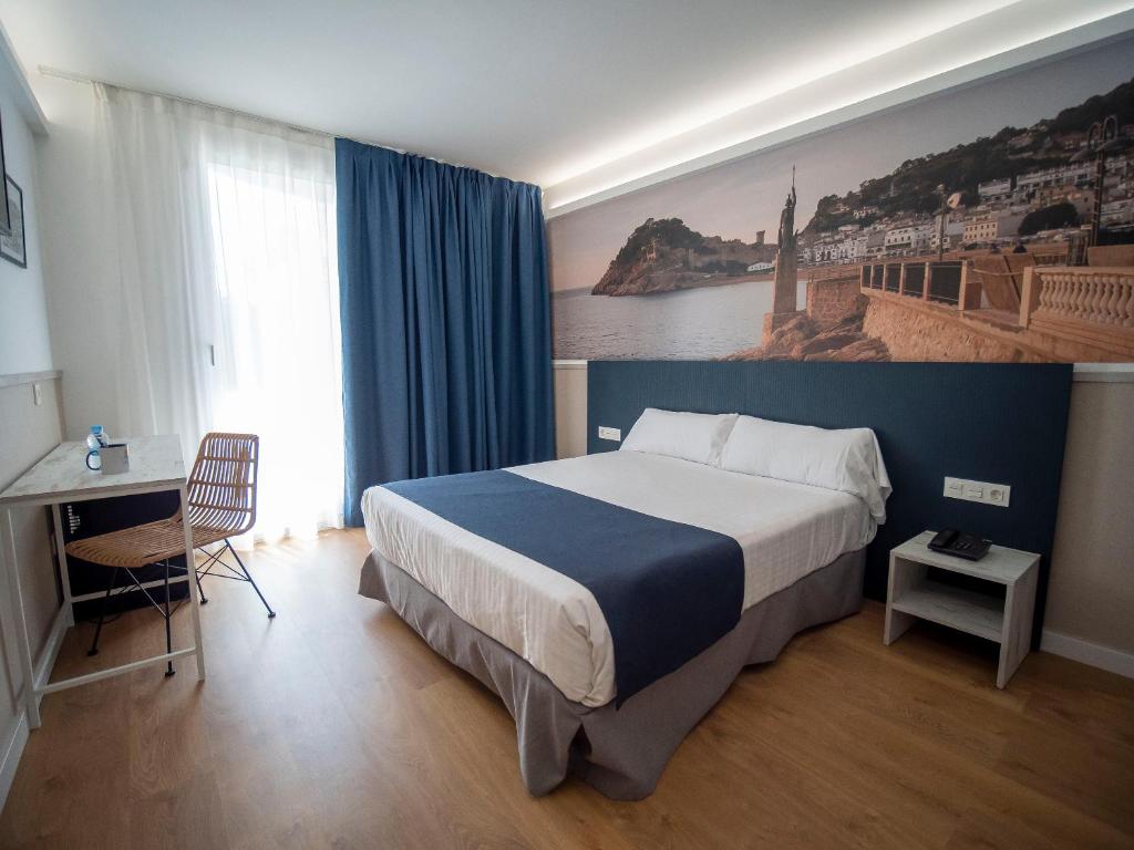 a hotel room with a large bed and a desk at Hotel Don Juan Tossa in Tossa de Mar