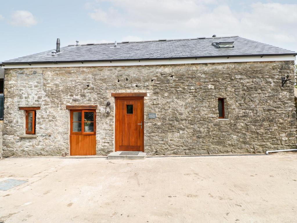 a stone building with two wooden doors and aphalt at Lime Kiln Cottage in Bridgend