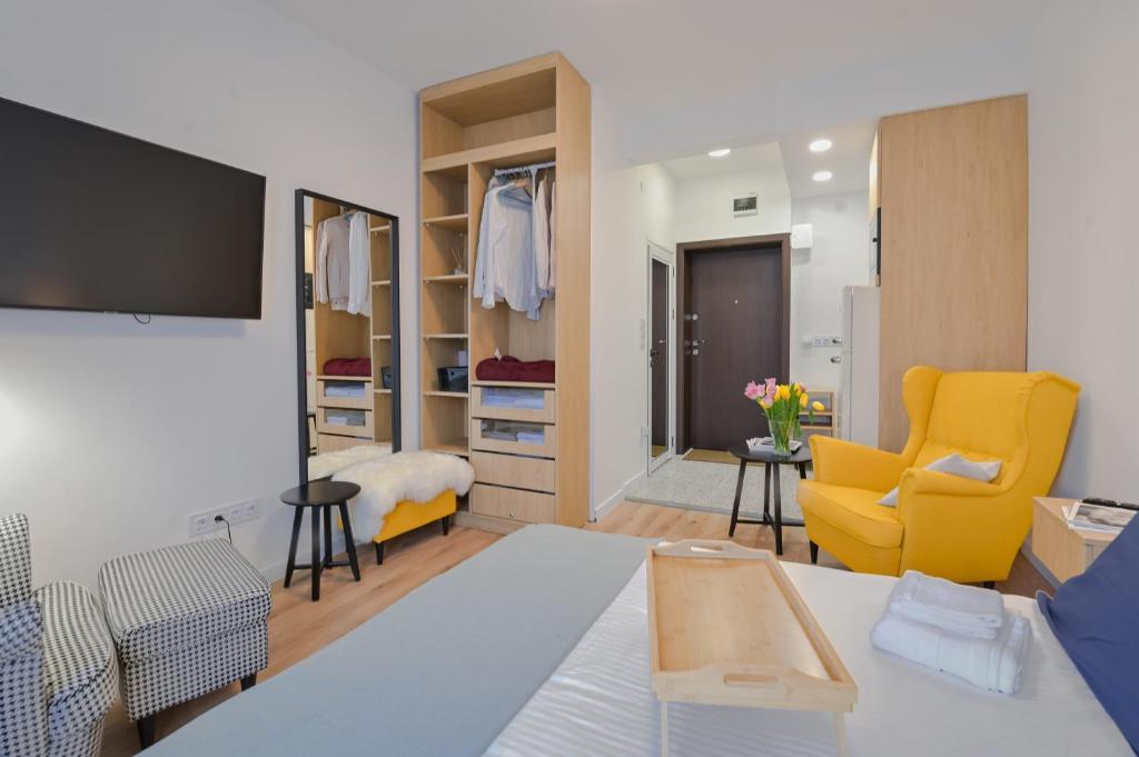 a living room with a yellow chair and a closet at Cosy and Stylish Studio next to Sofia's Central Market Hall in Sofia