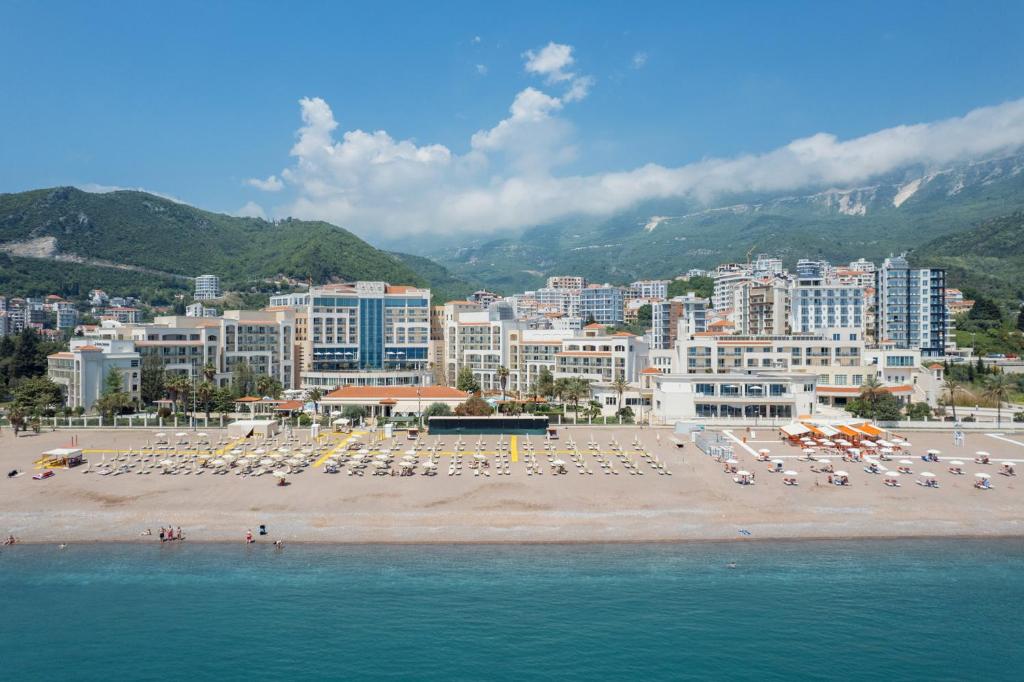 einen Strand mit Stühlen, Sonnenschirmen und Gebäuden in der Unterkunft Apartments TQ Splendid in Budva