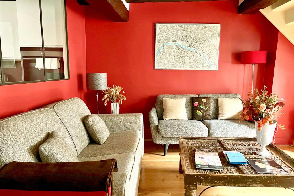 パリにあるLouvre Penthouse PadATerre Owner Direct since 1999の赤い壁のリビングルーム(ソファ、テーブル付)