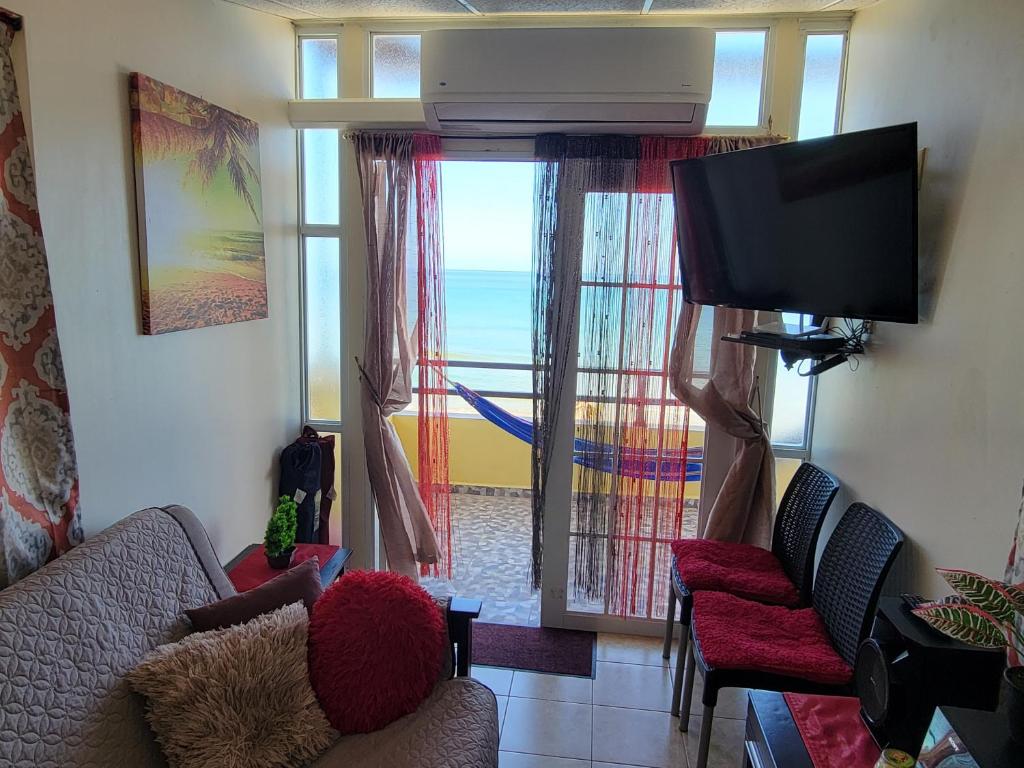 uma sala de estar com uma televisão e uma porta de vidro deslizante em Yaeliz Front Beach em Aguada