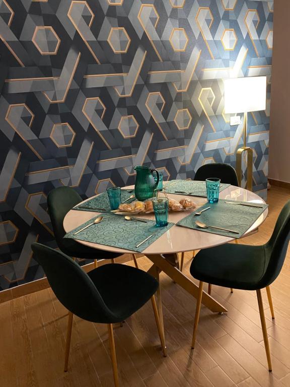 a dining table with four chairs and a blue wall at B&B Smeralda in Villa San Giovanni