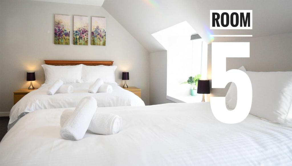 Rooms on the High Street في بورتري: سريرين بيض في غرفة نوم مع علامة الغرفة