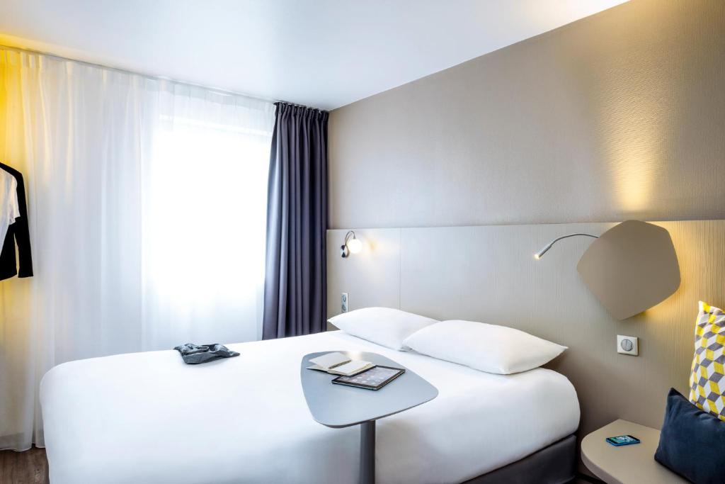 a hotel room with a white bed and a table at ibis Styles Paris Bercy in Paris