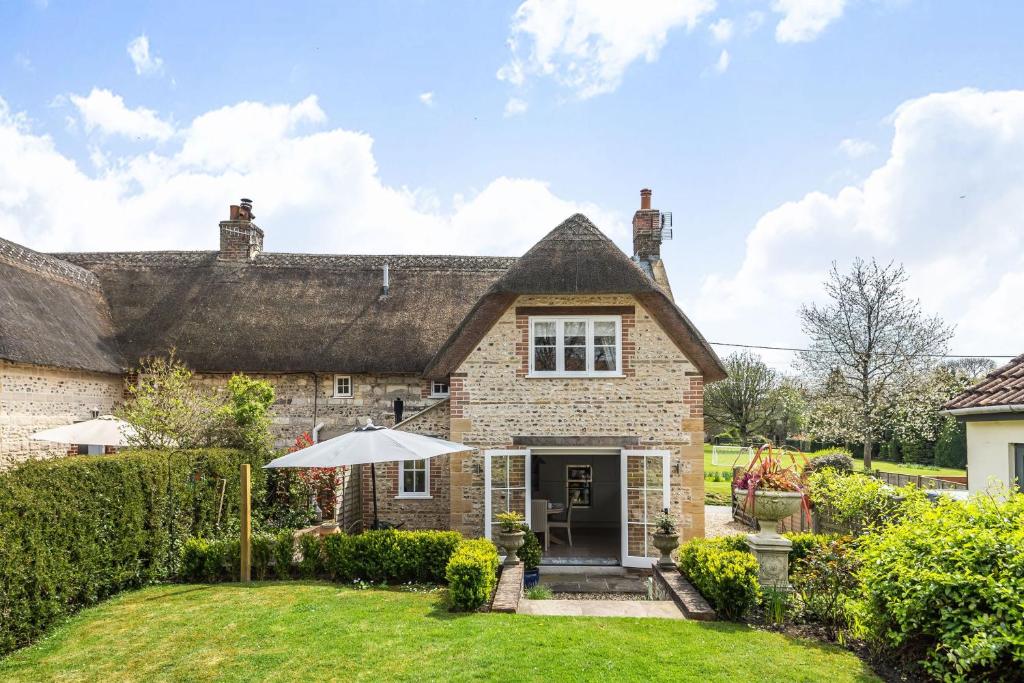 an old stone house with a thatched roof at Coombe Cottage in Dorchester