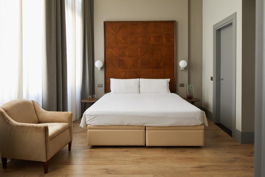 a bedroom with a large bed and a chair at Hotel Dei Dragomanni in Venice
