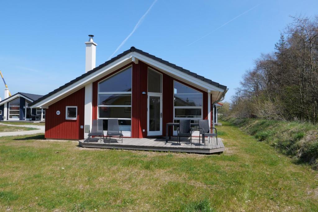 une petite maison rouge avec une terrasse dans l'herbe dans l'établissement Resort 2 Ocean Cottage A 87, à Großenbrode