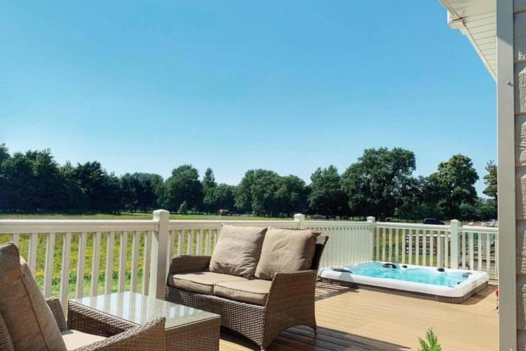 un patio avec un canapé et une table sur une terrasse dans l'établissement Heathery Lodge with Hot Tub, à York