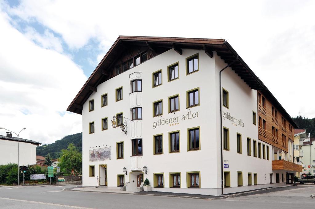 ein weißes Gebäude mit braunem Dach in der Unterkunft Hotel Goldener Adler Wattens in Wattens