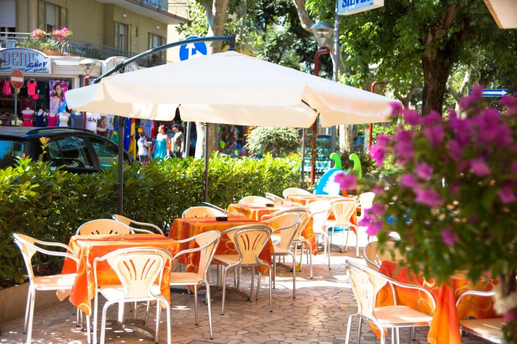 a group of tables and chairs with an umbrella at Hotel Silvia in Misano Adriatico