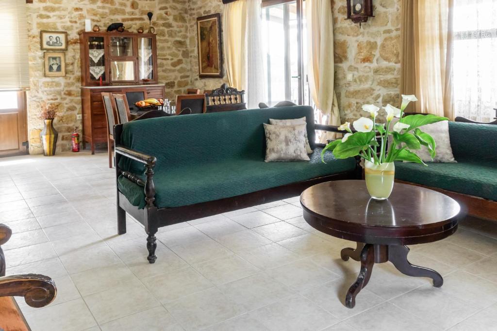 a living room with a green couch and a table at Charming Stone House With Swimming Pool in Archanes