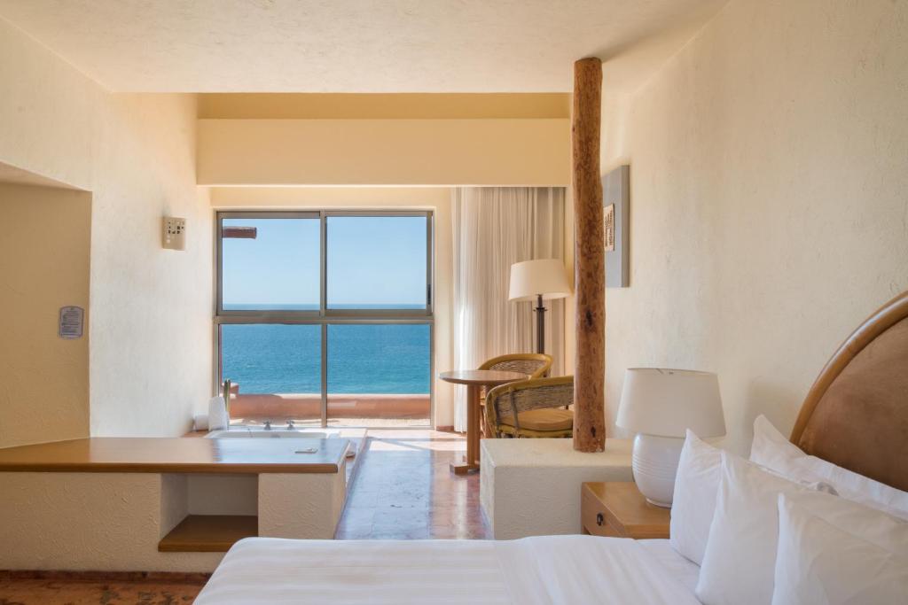 a hotel room with a bed and a view of the ocean at Club Regina Los Cabos in San José del Cabo