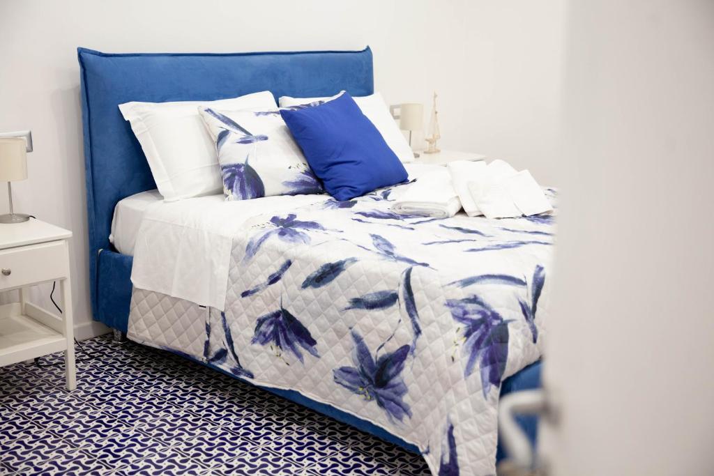 een blauw en wit bed met blauwe en witte lakens en kussens bij White Blu House - Massa Lubrense Sorrento in Massa Lubrense