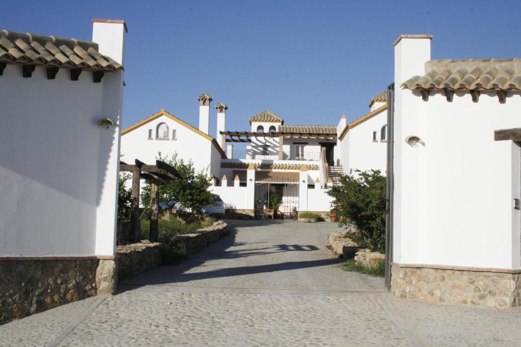 une maison blanche avec un portail et une allée. dans l'établissement El Fogón del Duende, à Arcos de la Frontera