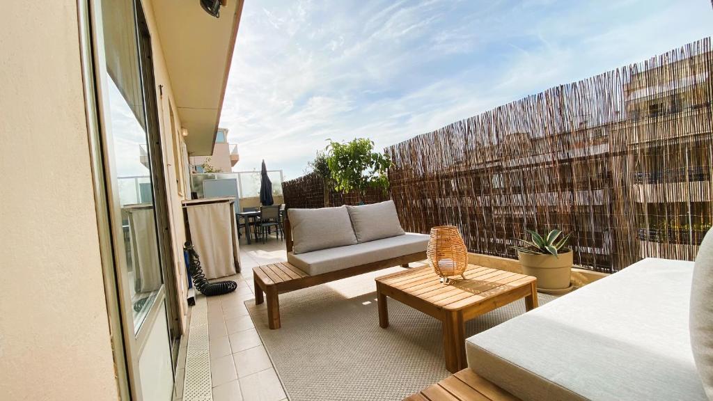 een balkon met een bank en een stoel op een patio bij T2 Bricka La Terrasse de la plage, Moderne, équipé, Lumineux in Antibes