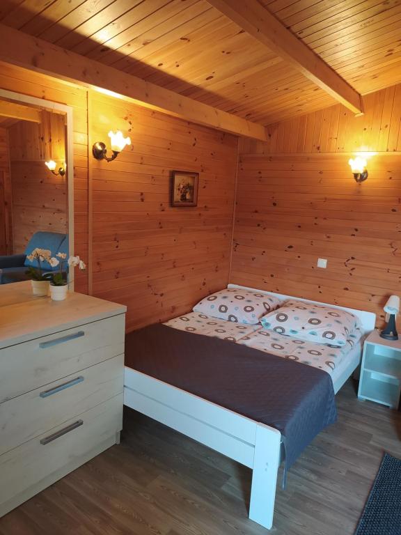 um quarto com uma cama num chalé de madeira em Domki Letniskowe Nika em Mikolajki