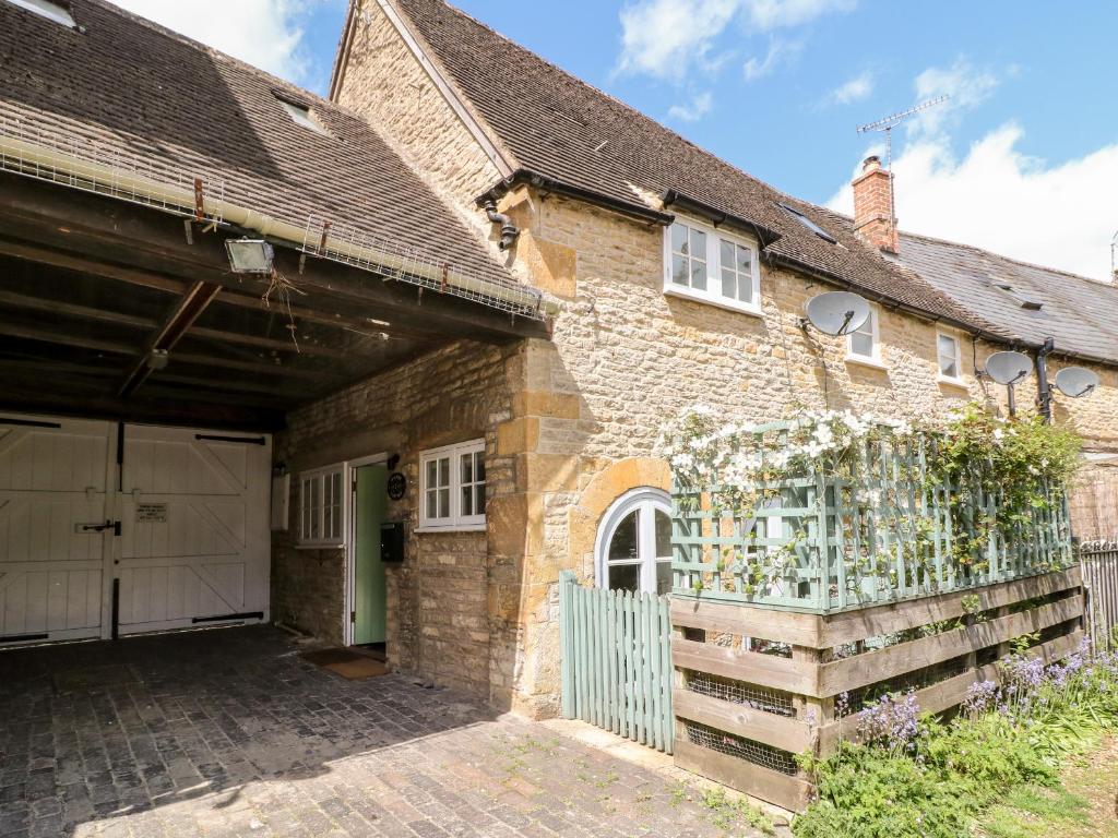 una vieja casa de ladrillo con una puerta y un garaje en 1 Manor Cottage en Stow on the Wold