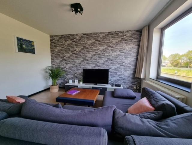 a living room with a couch and a tv at Maison Noordburg Veurne in Veurne