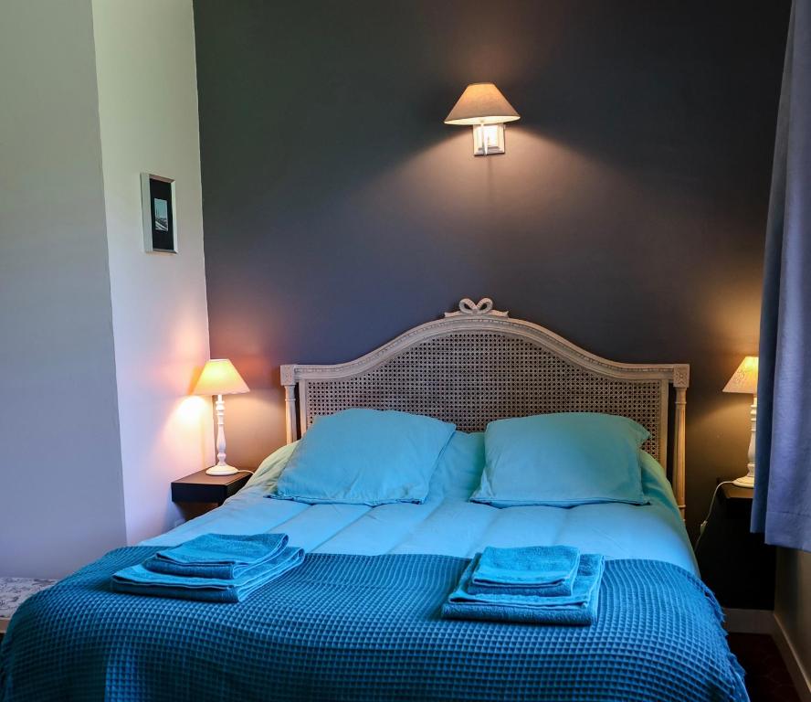 a bedroom with a bed with blue sheets and blue pillows at Domaine de Montbarri in La Tour-sur-Orb