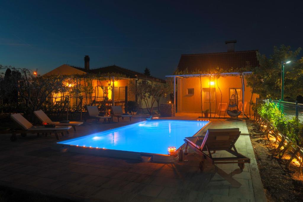 a swimming pool in a yard at night at Holiday house Olive Tree in Kaočine