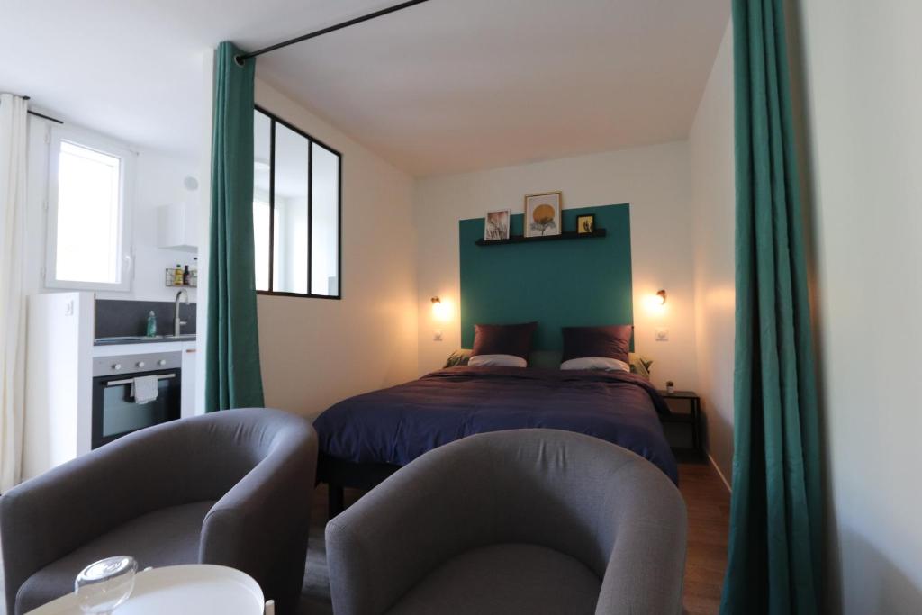 a bedroom with a bed and two chairs at Studio tout confort - Climatisation, parking, wifi in Gréoux-les-Bains