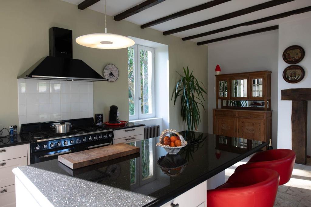 Il comprend une cuisine équipée d'une cuisinière et d'un comptoir avec des chaises rouges. dans l'établissement La Petite Ecole, à Treignac