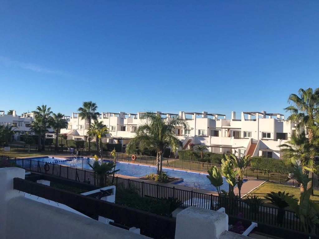 vistas a una piscina con palmeras y edificios en "La Piña" Condado Golfresort 1574, en Alhama de Murcia