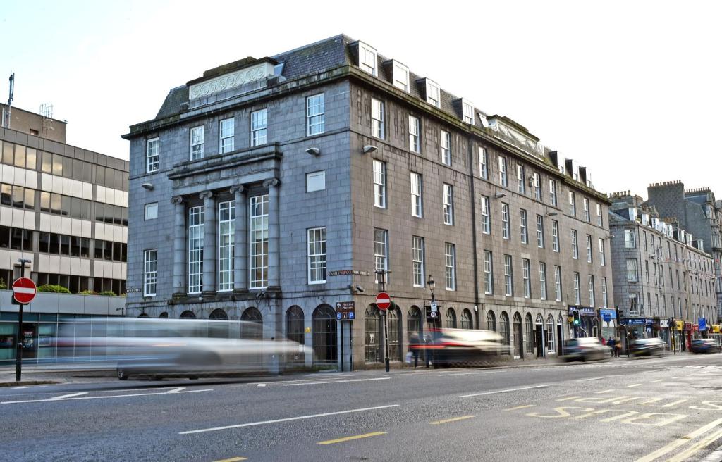 a building on a city street with cars driving past it at Royal Athenaeum Suites in Aberdeen