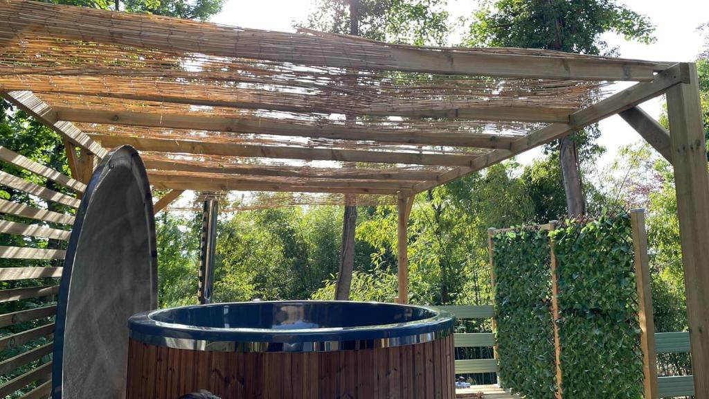 wanna z hydromasażem pod drewnianą pergolą w obiekcie La cabane du Panda w mieście Abrest