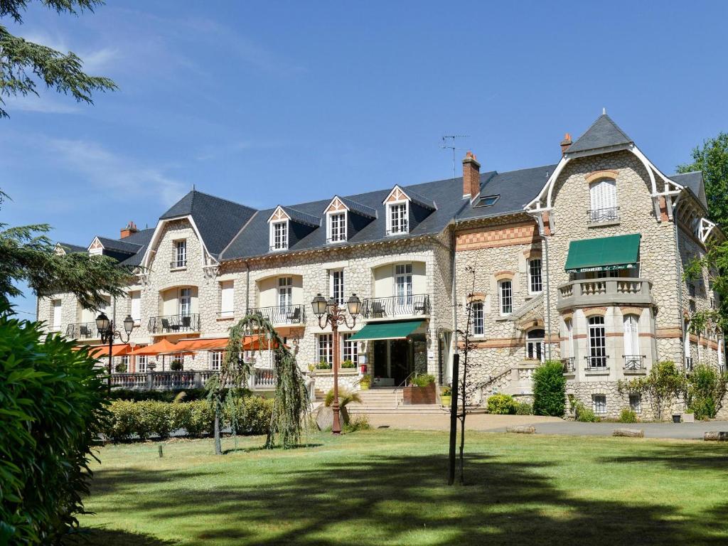 a large stone building with a lawn in front of it at Logis Hôtel Restaurant Le Parc in Salbris