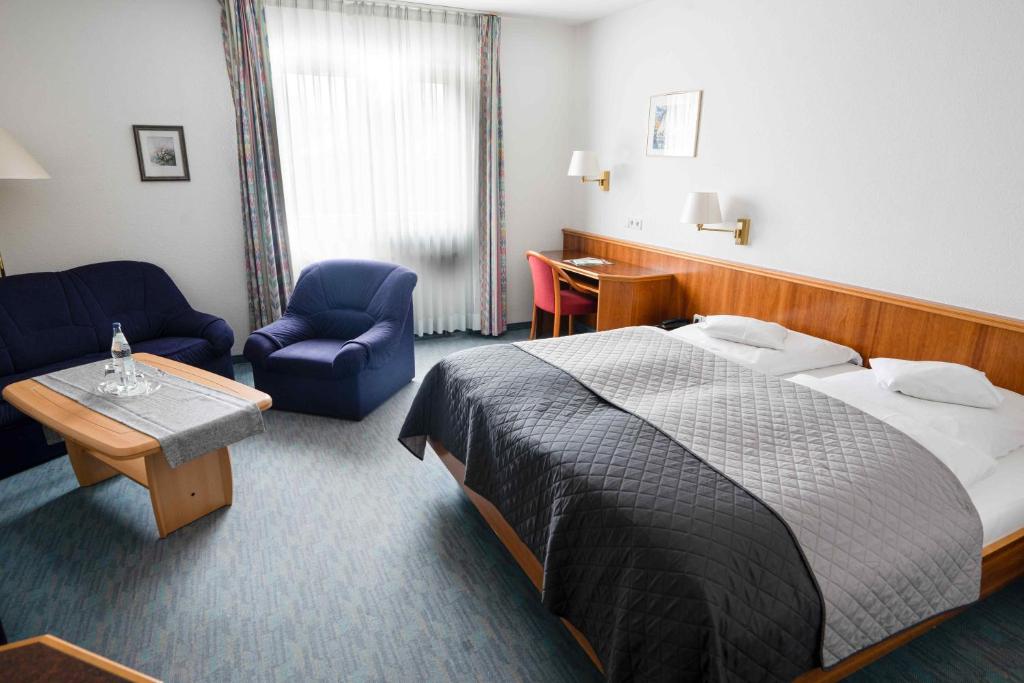 a hotel room with a bed and a table and chairs at Hotel Maselheimer Hof in Maselheim