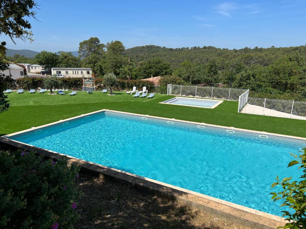 a large swimming pool in a yard with chairs at Joli Mobil-Home de Vacances, Ideal pour les familles in Rocbaron