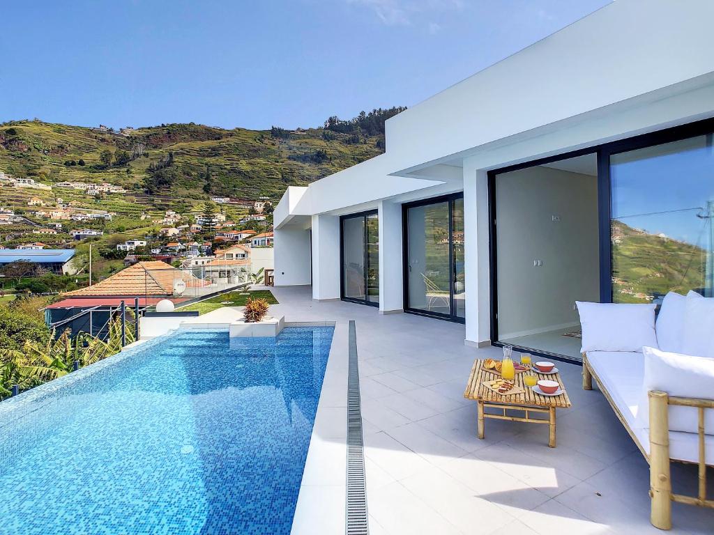 a villa with a swimming pool and a living room at Noah - Private Sunset Hideaway by LovelyStay in Arco da Calheta