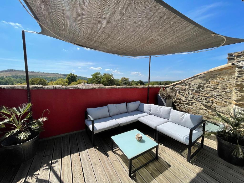 a patio with a couch and a table on a deck at La Maison de Sofia in Vallabrix